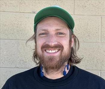 Smiling man with hair to his shoulders with a serv pro hat on