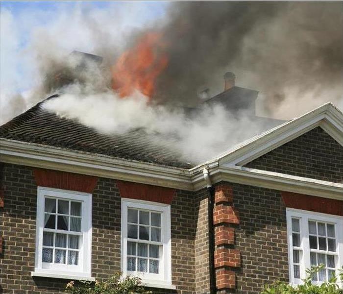 Image of a house on fire. Smoke is coming out of a upstairs window
