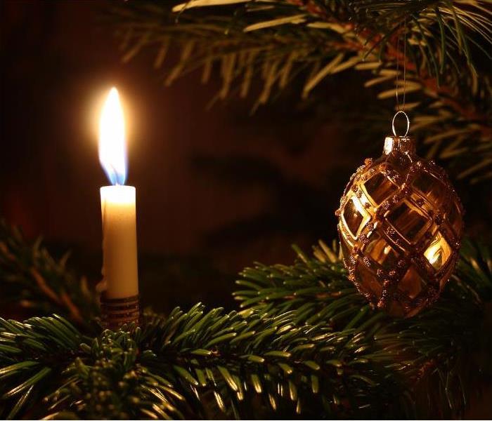 A lit candle on a Christmas tree.