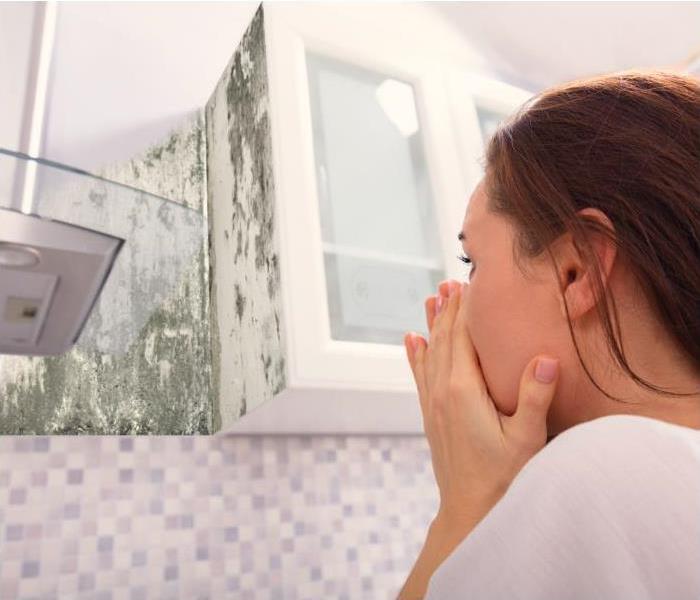 A woman amazed how mold grows on her wall